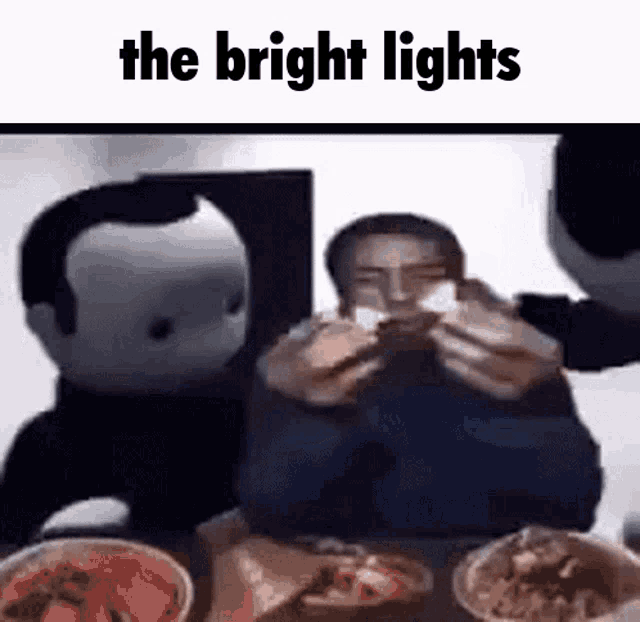 a man is sitting at a table with a bunch of food and the words the bright lights above him