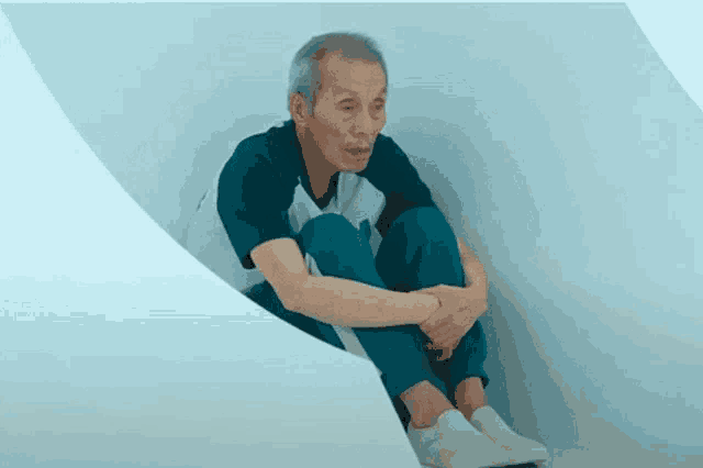 an elderly man is sitting on the floor with his legs crossed .
