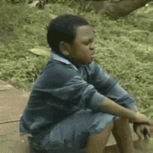 a young boy is sitting on the ground with his legs crossed .