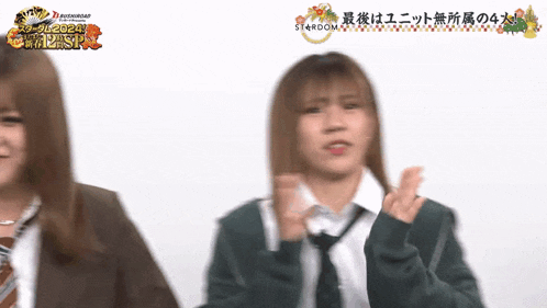 two girls in school uniforms are standing next to each other in front of a sign that says stardom on it