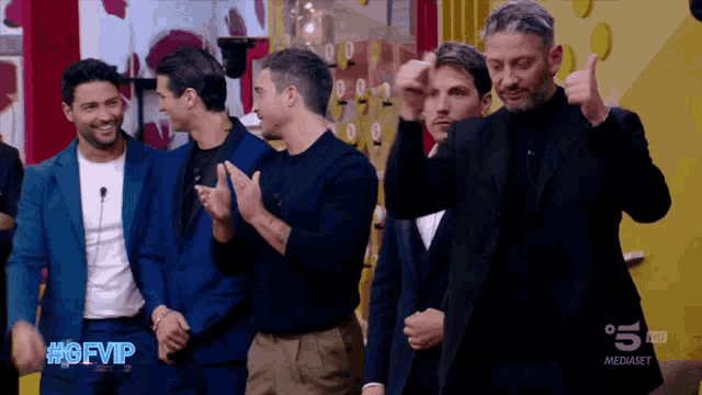 a group of men are standing in front of a yellow wall with the words #gfvip on the bottom