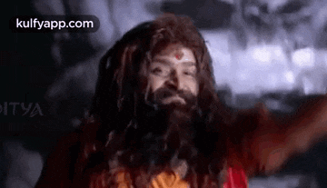 a man with dreadlocks and a beard is wearing a wig and a red robe .