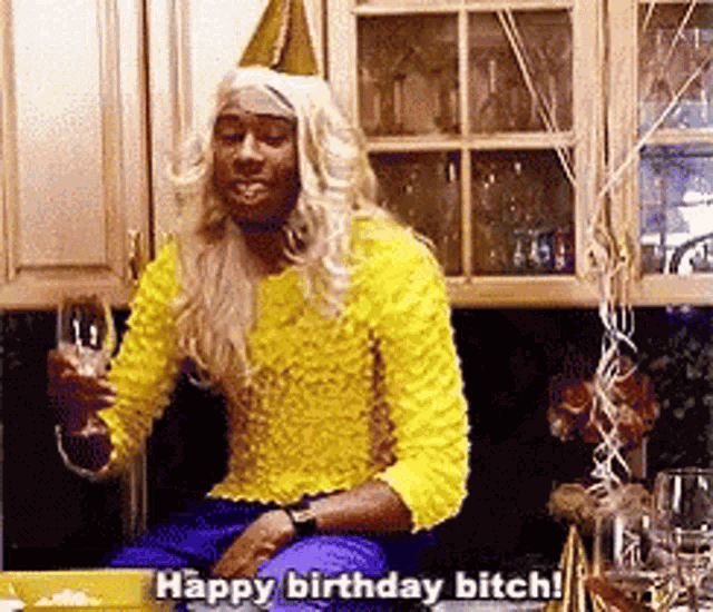 a man in a yellow sweater is holding a glass of wine and saying happy birthday bitch !