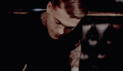 two men are sitting next to each other and one of them has a tattoo on his arm