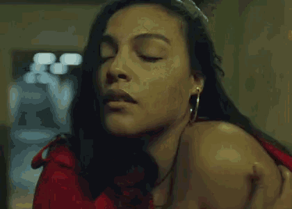 a woman in a red shirt is holding her chest with her hands .