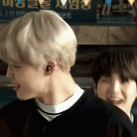 a man wearing ear buds is standing next to another man