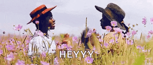 a couple of people standing in a field of flowers .