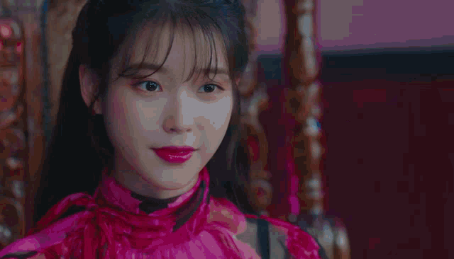a woman wearing a pink dress and red lipstick smiles