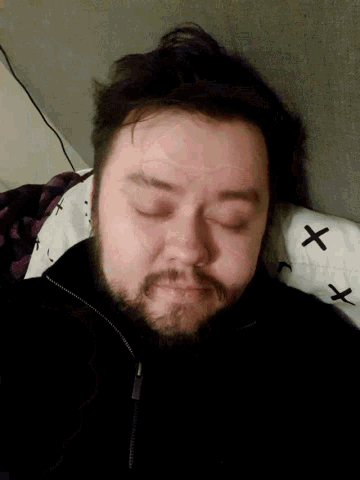 a man with a beard is sleeping on a white blanket with crosses on it