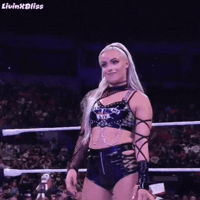a female wrestler is standing in a wrestling ring .