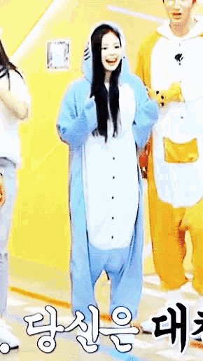 a girl in a blue and white animal costume stands in front of a yellow wall