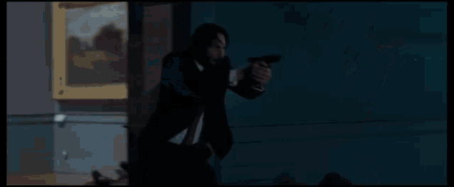 a man in a suit is holding a gun in front of a statue