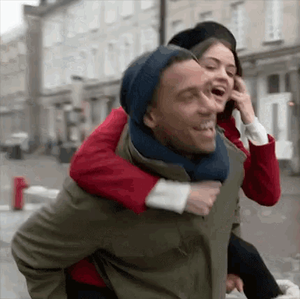 a man is giving a woman a piggyback ride on the street