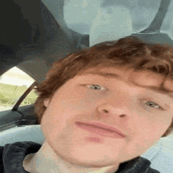 a young man with red hair is sitting in the back seat of a car .