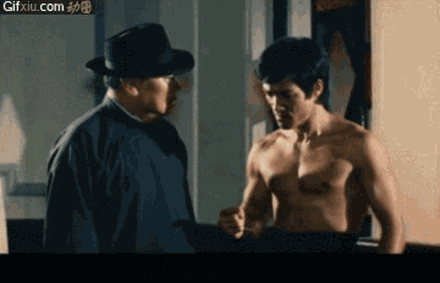 a shirtless man is standing next to another shirtless man in a hat .