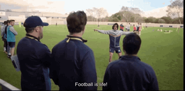 a group of men standing on a soccer field with the words " football is life " on the screen