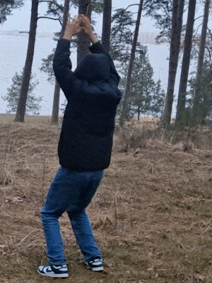 a man in a black jacket is standing in the woods