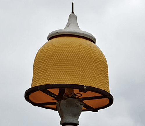 a street light with a yellow shade and a white top that says ' sd ' on it