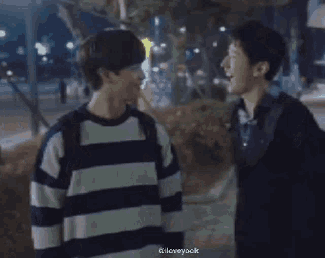 a blurry picture of two men standing next to each other in a park at night .