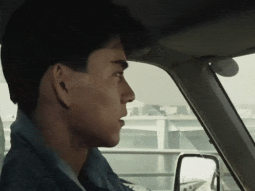 a man in a car is looking out the window at something