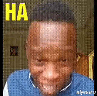 a man in a blue sweater is making a funny face with the word ha written on his forehead .