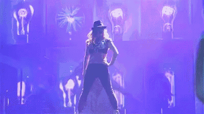 a woman is dancing on a stage in front of a purple background .