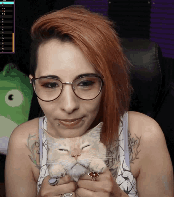 a woman with red hair and glasses holds a cat in her arms