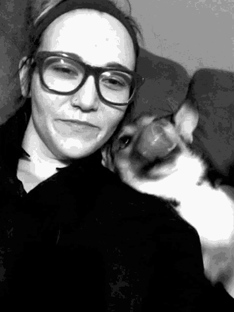 a woman wearing glasses and a headband is posing for a picture with her dog .