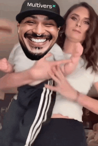 a man wearing a hat with the word multivers on it is being held by a woman