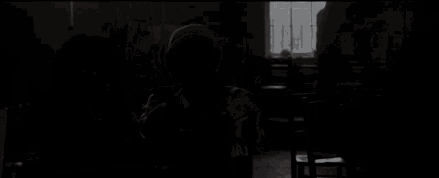a man in a hooded sweatshirt is sitting in a dark room