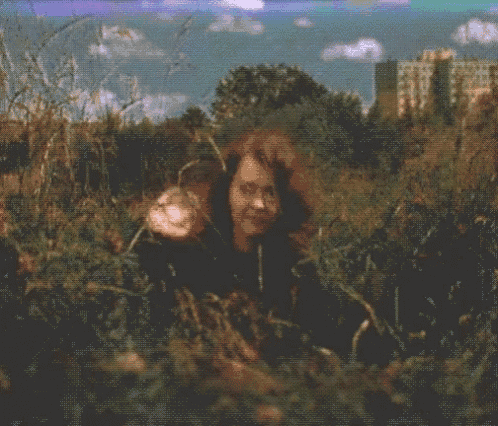 a blurry picture of a woman in a field with a city in the background