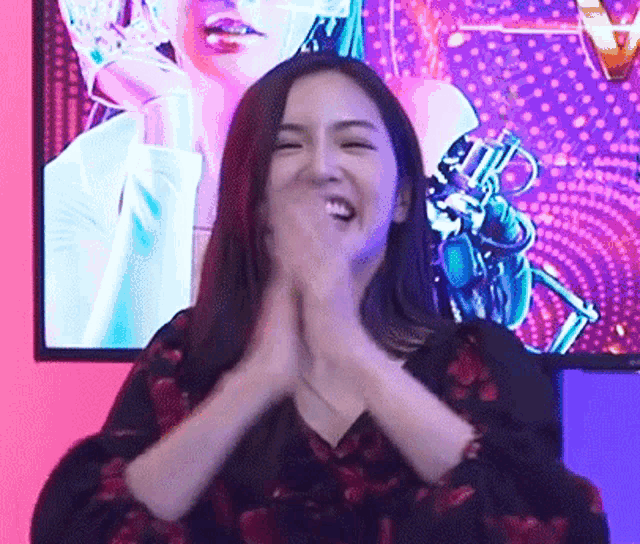 a woman is clapping in front of a screen with a picture of a woman on it