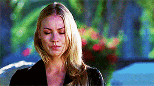 a woman with blonde hair is wearing a black jacket and looking down