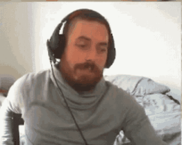 a man with a beard wearing headphones and a grey shirt