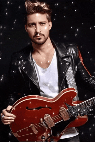a man in a black leather jacket holds a red guitar