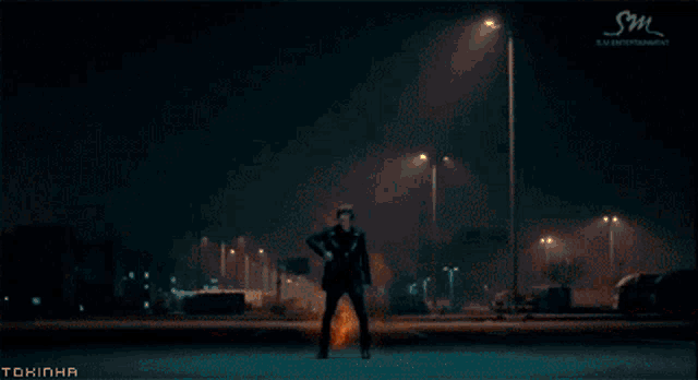 a man is standing in front of a large fire with sm entertainment written in the corner