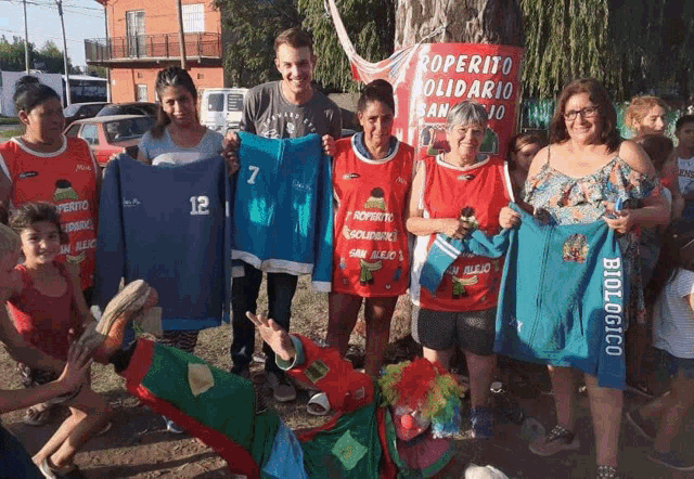 a group of people holding up shirts that say biologico on them