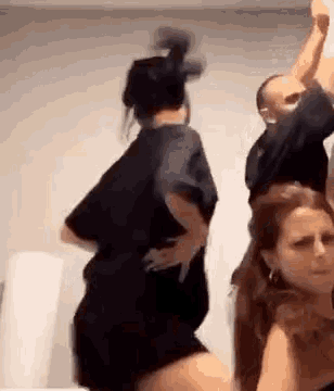 a group of people are dancing together in a room while a man holds a baby .