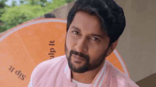 a man with a beard is wearing a pink jacket and a white shirt .