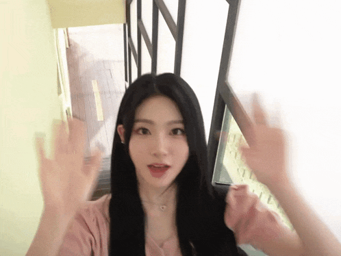 a woman in a pink shirt is waving her hands