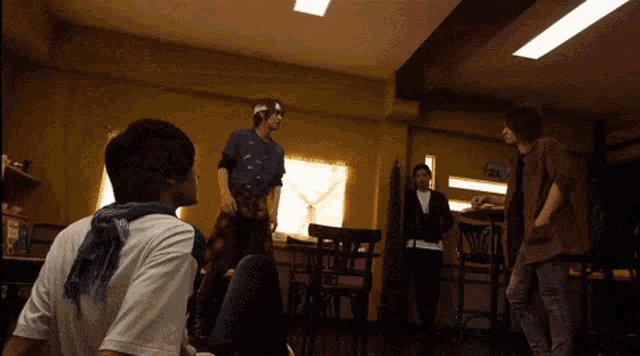 a man in a purple shirt stands in a room with other men