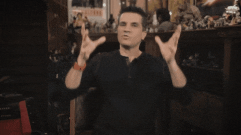 a man in a black shirt is making a peace sign with his hands