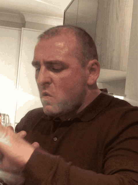 a man in a brown shirt is sitting at a table with his eyes closed