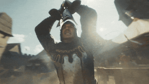 a man in a knight 's armor is holding a sword over his head