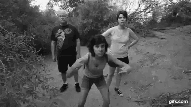 a black and white photo of a group of people standing next to each other on a dirt road .