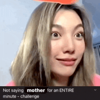 a woman is making a funny face while holding an orange object on her head .