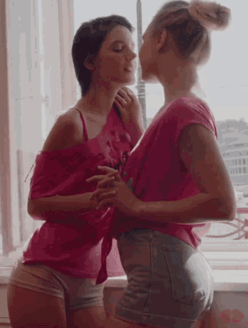 two women in pink shirts and shorts are kissing