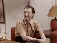 a man with a mohawk is smiling while sitting at a desk