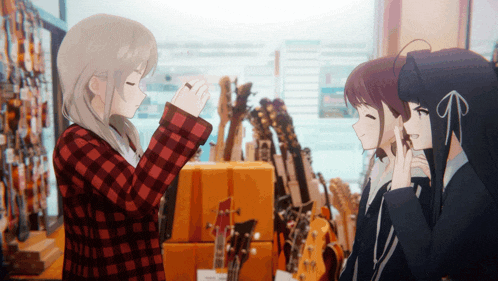 a girl in a red and black plaid shirt talks to two other girls in a store