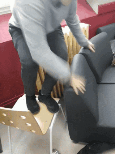 a man standing on a chair next to a black couch